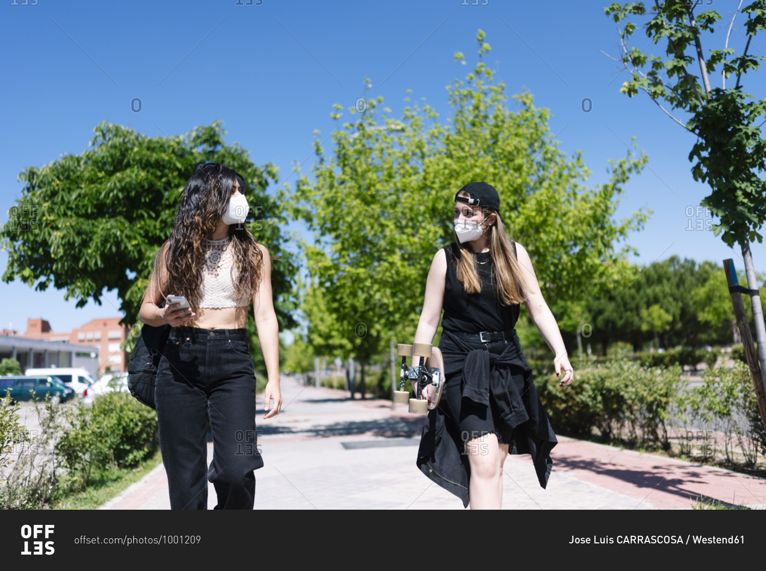 Two women with protective face masks walking in the street