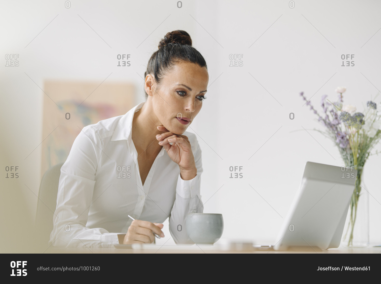 Businesswoman looking at laptop while working on desk in home office