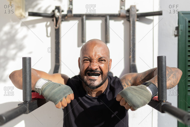 Close-up of bald mature man with mouthguard exercising against wall in yard