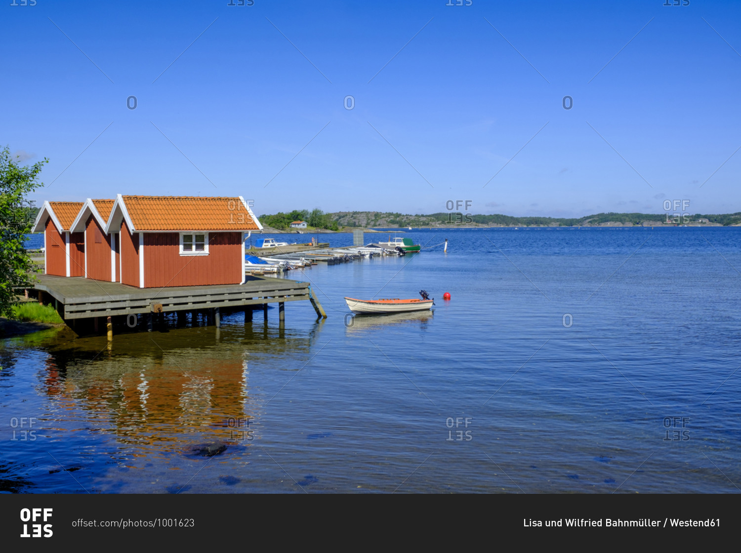 Clear blue sky over coastal boathouses and marina in summer