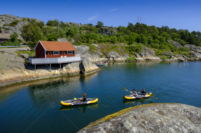 Kayakers passing small coastal stilt house