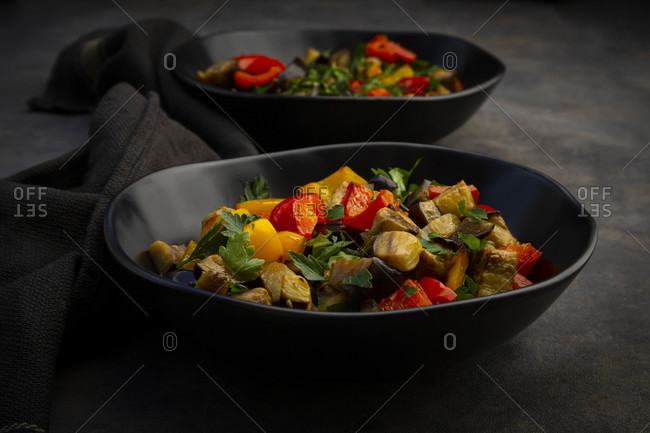 Two bowls of stir-fried vegan salad with eggplants- paprika and parsley