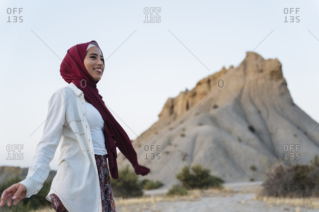 Smiling young tourist woman wearing Hijab in desert landscape