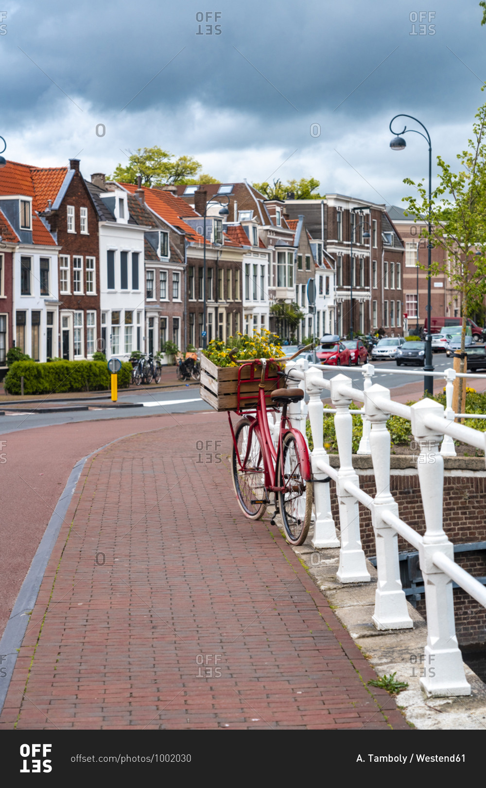 Netherlands- North Holland- Haarlem- Bicycle parked along railing of canal bridge with houses along Hooimarkt street in background
