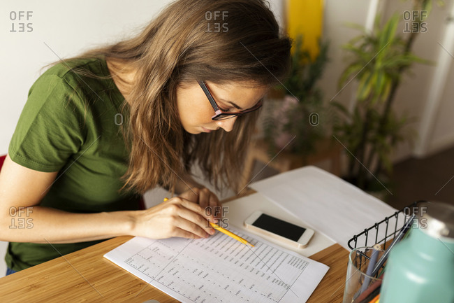 Businesswoman reading document on desk in home office