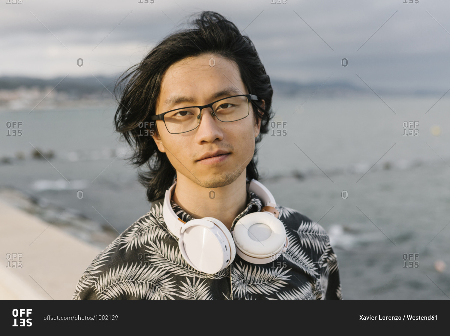 Close-up of young man with headphones against sea in city