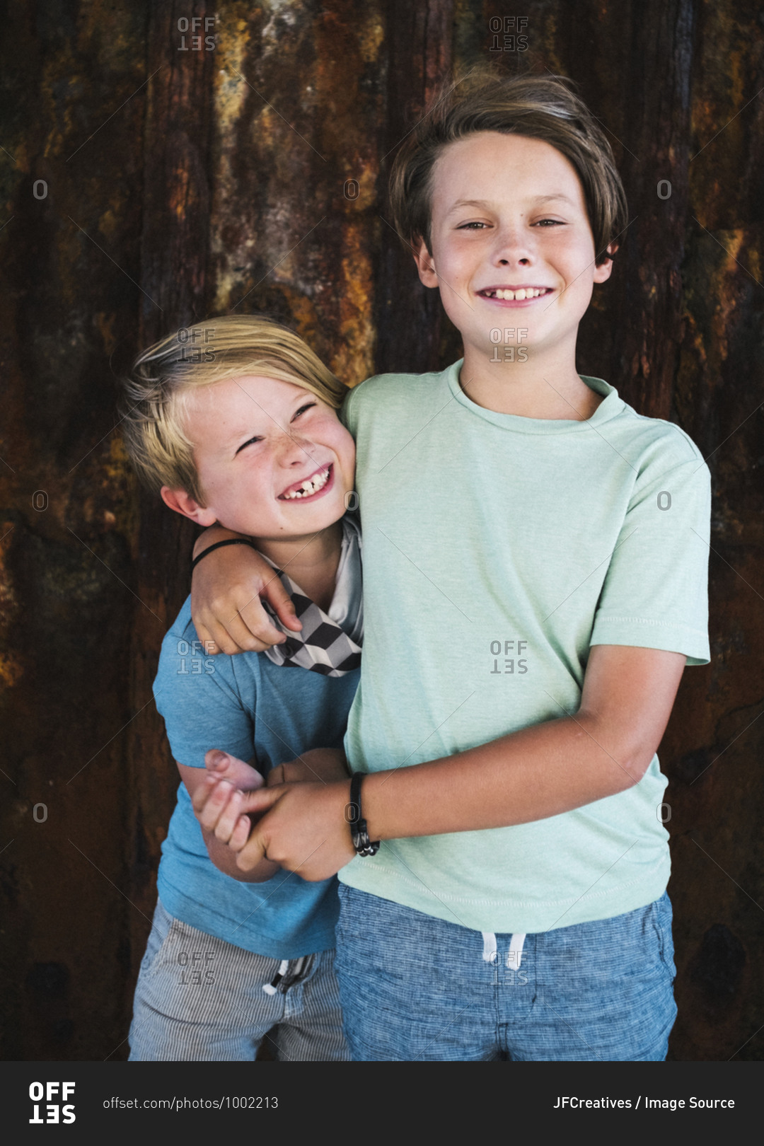 Portrait of two smiling boys, arm around shoulder, looking at camera.