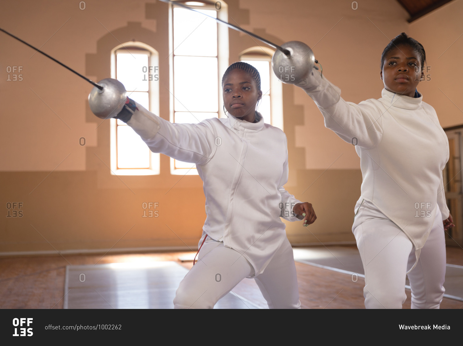 African american sportswomen wearing protective fencing outfits during