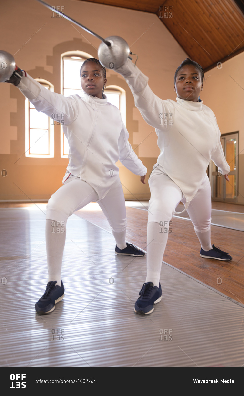 African american sportswomen wearing protective fencing outfits during