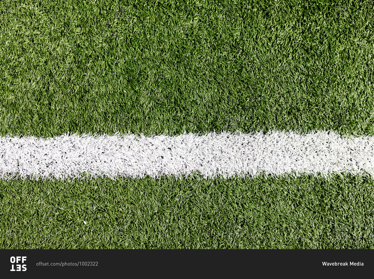 Close up of a white line drawn on a grass football pitch on a sunny day. Sports stadium football ground.