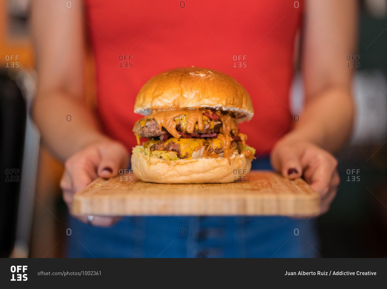 Ethnic waitress catering clients in cafe with burger on wooden cutting board