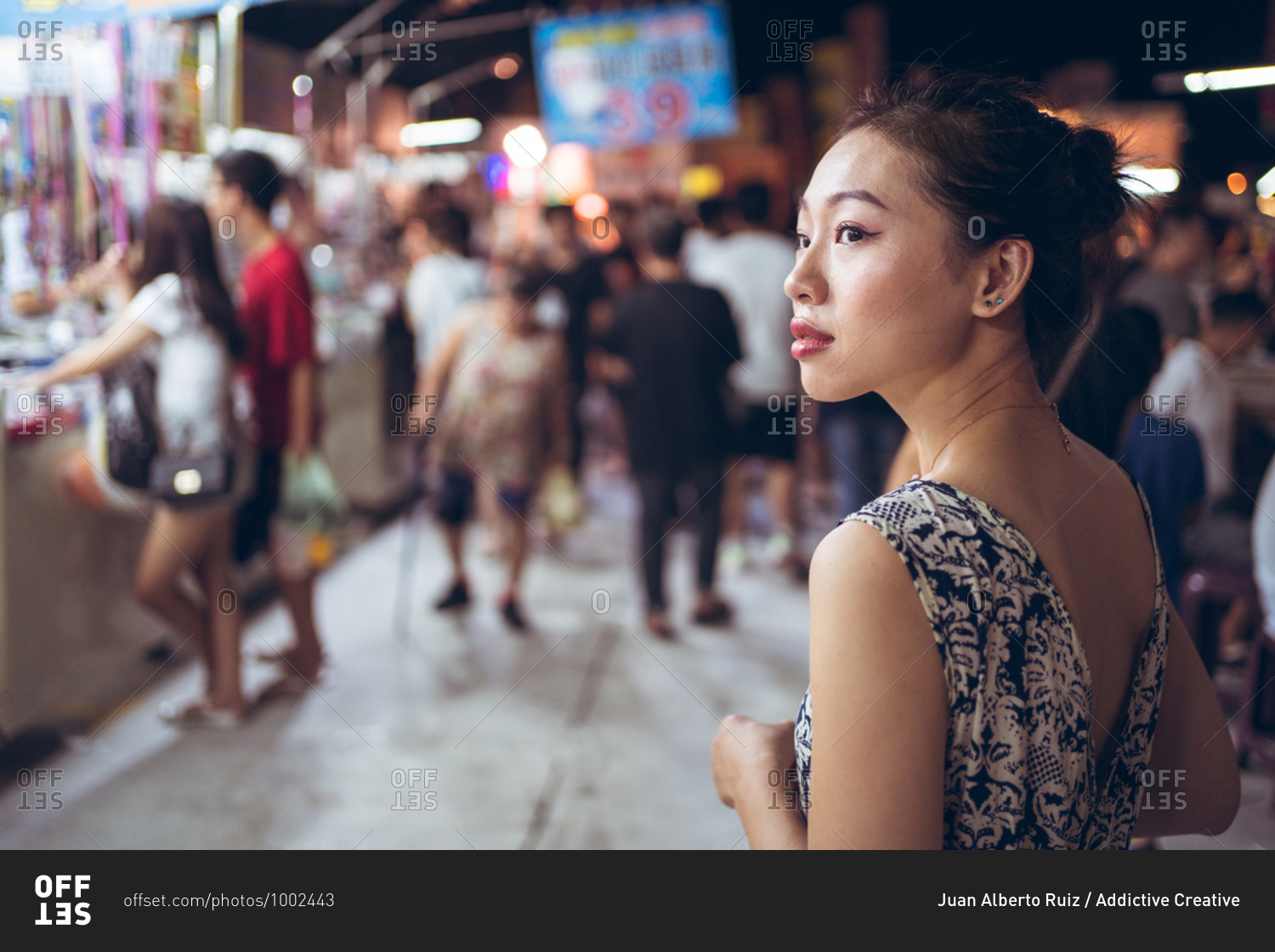 Side view of confident ethnic female standing on crowded\
street in Night Market in Taiwan and looking away stock photo -\
OFFSET