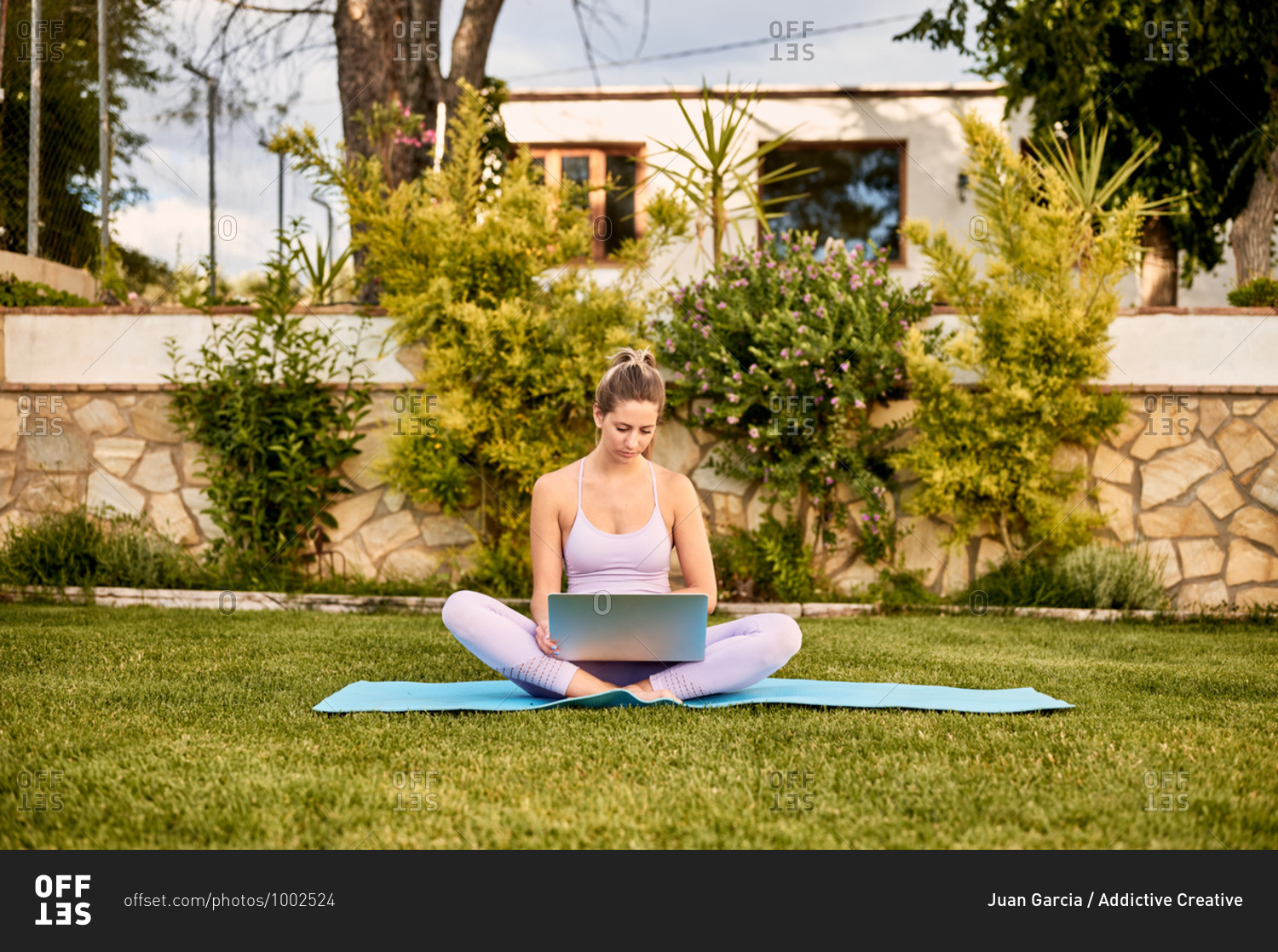 Calm female in sportswear sitting barefoot on mat and choosing online tutorial for practicing yoga