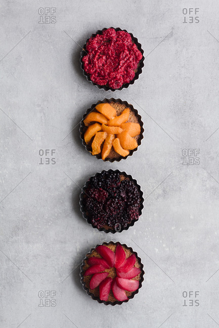 Top view of palatable pies with various ripe fruits and berries arranged in line on table