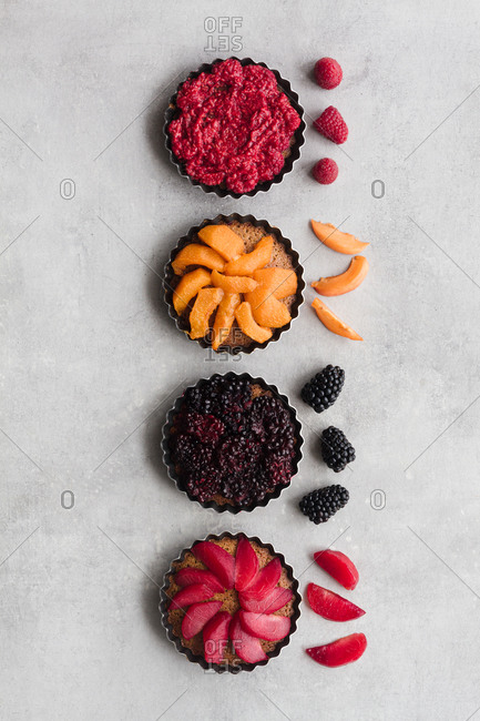 Top view of palatable pies with various ripe fruits and berries arranged in line on table