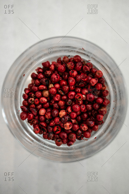 Top view of pile of dried red peppercorn placed inside glass jar on table