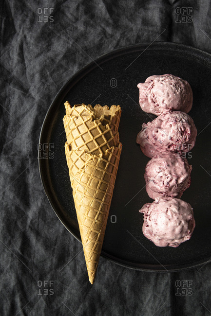 From above of delicious homemade cherry ice cream scoops arranged on table with waffle cones