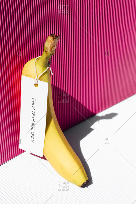 Banana with tag private usage only against pink background