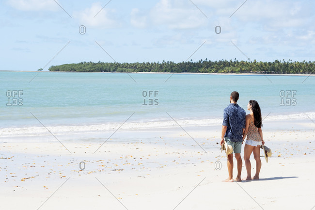 July 18, 2016: A good-looking Hispanic (Latin) couple on a deserted beach with backs to camera, Brazil, South America