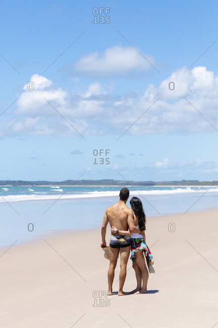 September 25, 2018: A good-looking Hispanic (Latin) couple on a deserted beach with backs to camera, Brazil, South America