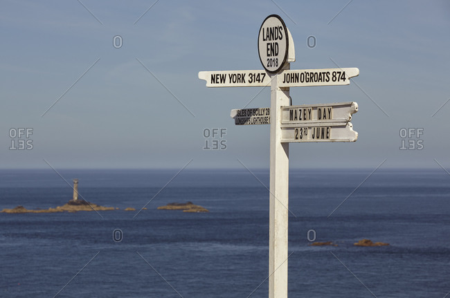 A signpost at Land's End, Britain's most southwesterly point, with Longships Lighthouse and the Atlantic Ocean behind, Cornwall, England, United Kingdom, Europe