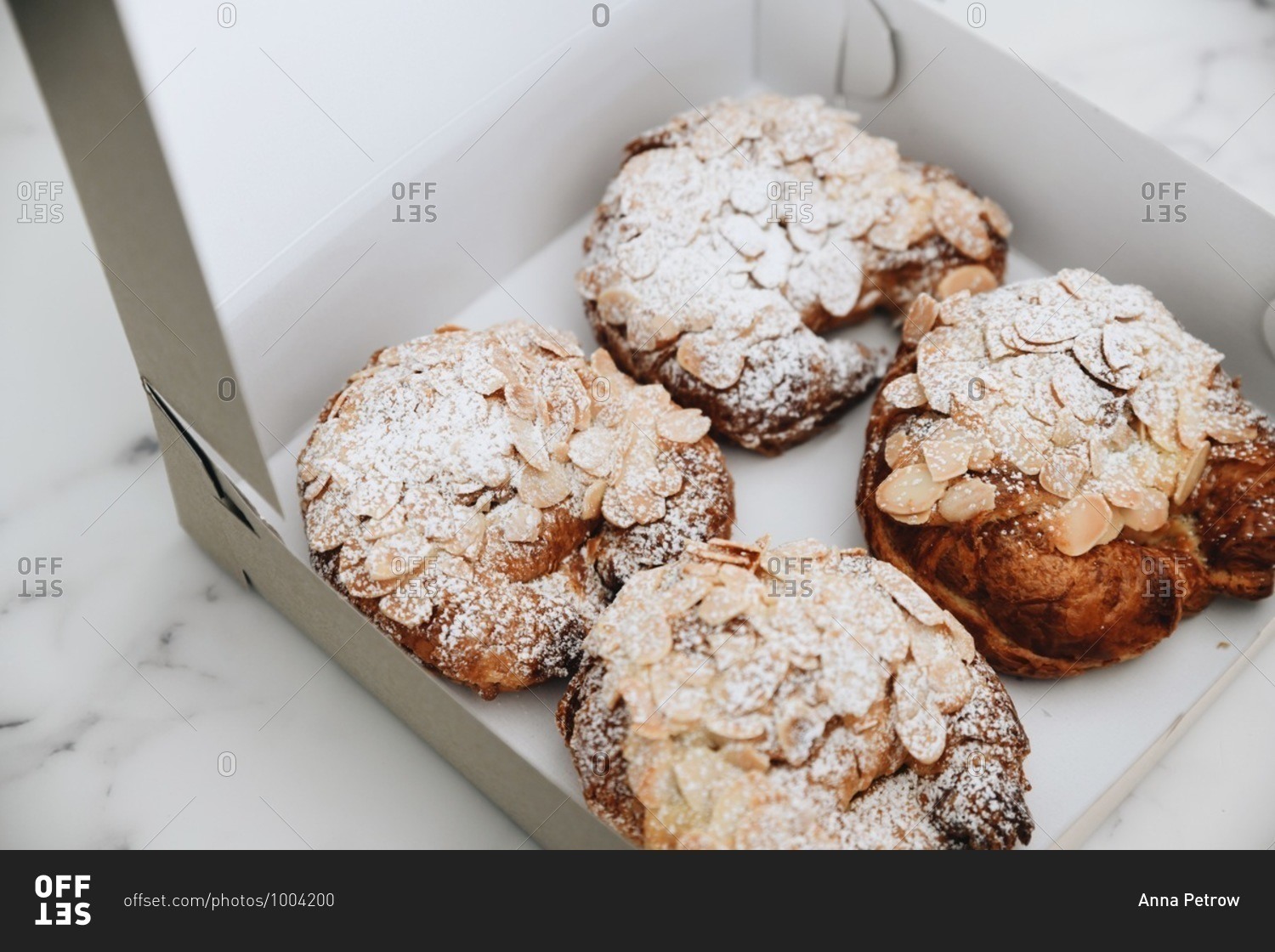 Almond pastries covered in powdered sugar in a box