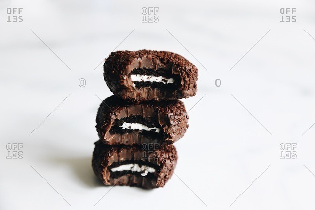 Chocolate sandwich cookie stuffed fudge cookies stacked on white surface