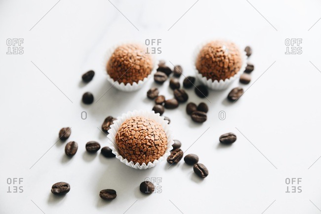 Cappuccino brigadeiros on white surface with coffee beans