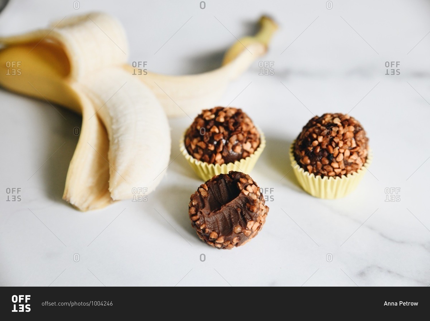 Bananas and nut brigadeiro missing a bite on marble surface