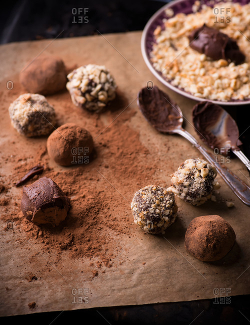 Assorted dark chocolate truffles with cocoa powder, biscuit and chopped hazelnuts on baking paper