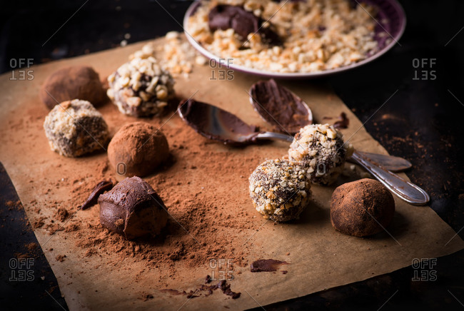 Variety of dark chocolate truffles with cocoa powder, biscuit and chopped hazelnuts on baking paper