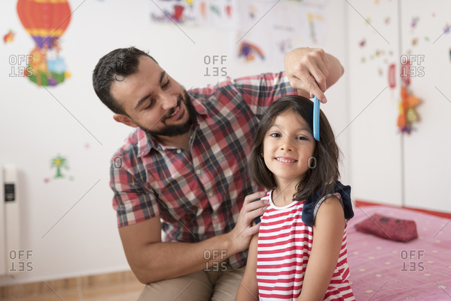 Father brushing his daughter's hair in her bedroom