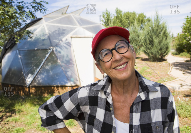 Senior woman gardening in geodesic dome, Santa Fe, NM.