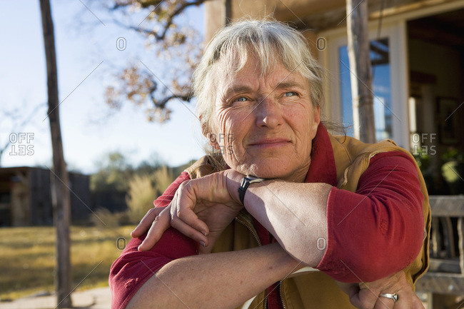 Mature woman at home on her property in a rural setting resting her chin on her hands