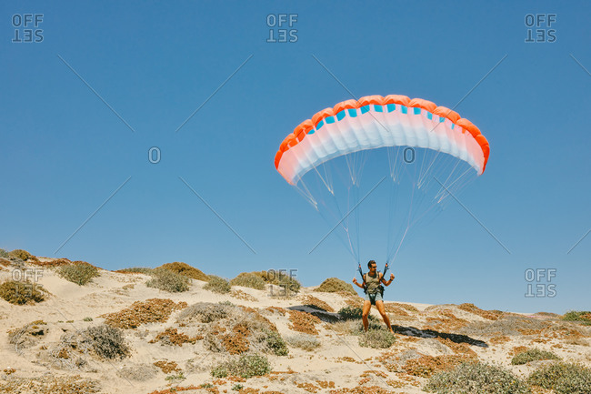 Young man paragliding during summer off cliffs in Baja, Mexico.