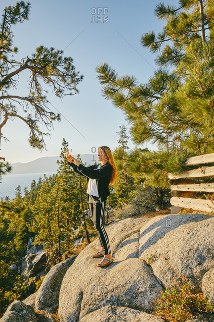 Young woman taking a picture of sunset over Lake Tahoe.