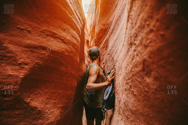 Young man exploring narrow slot canyons in Escalante, during summer