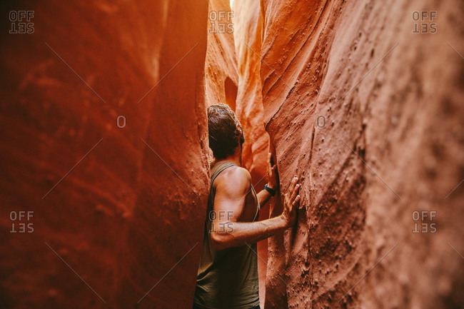 Young man exploring narrow slot canyons in Escalante, during summer