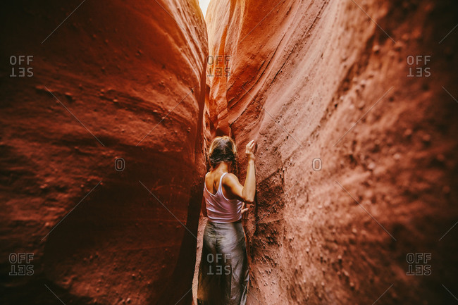 Young woman exploring narrow slot canyons in Escalante, during summer