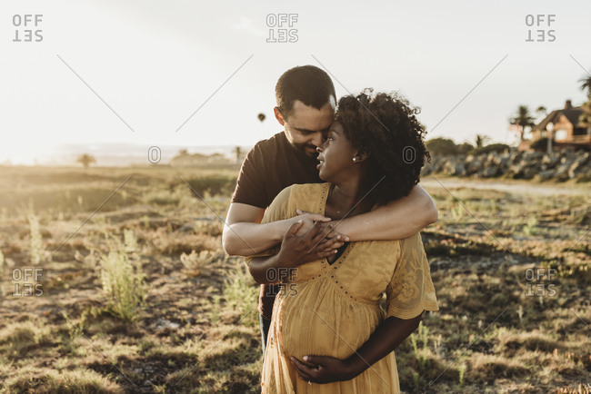 Young married couple embracing pregnancy at beach