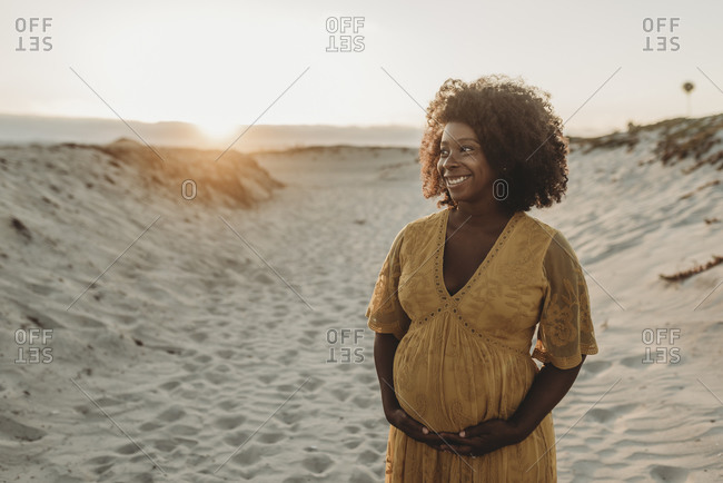 Portrait of pregnant mother in third trimester at beach at sunset