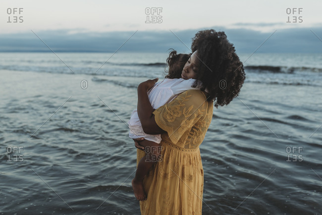Side view of mother and daughter hugging in the ocean