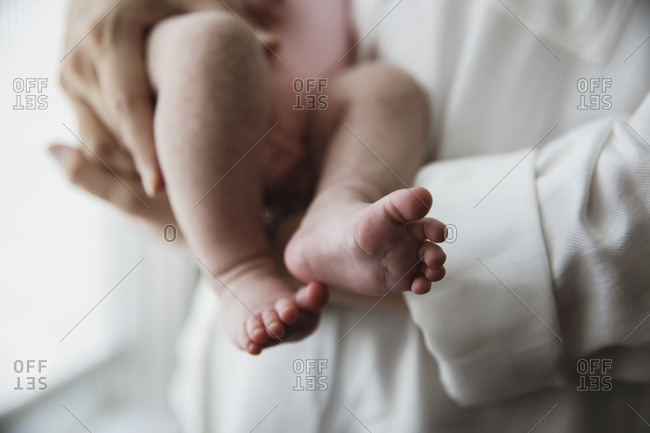 Parent holding newborn baby with focus on baby's feet