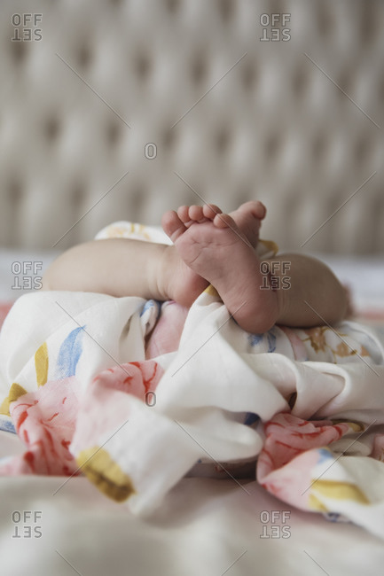 Baby feet and legs wrapped around floral sheets