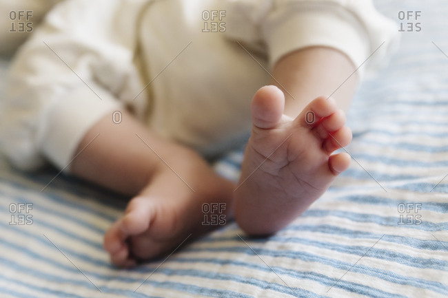 Close up a baby's feet lying on a striped blanket