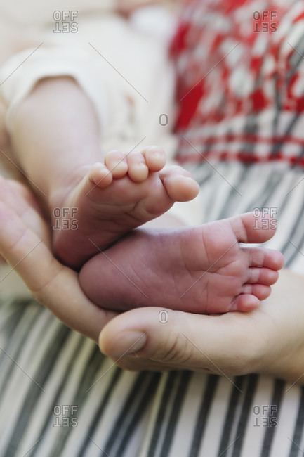 Mother holding newborn baby's foot in in hands