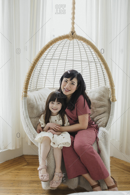 Mom and daughter swinging in chair swing inside