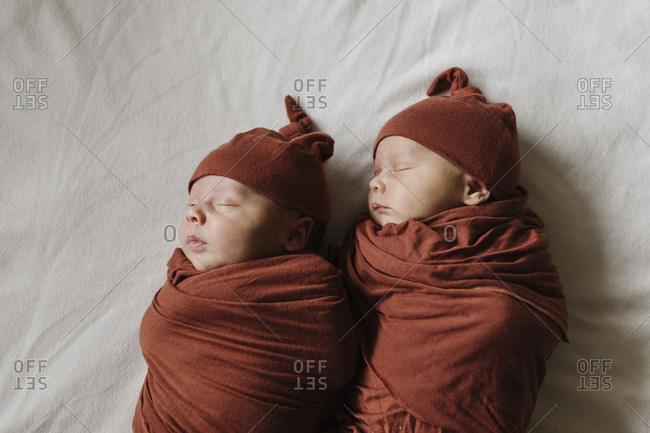 Identical twin baby boys sleeping on bed together
