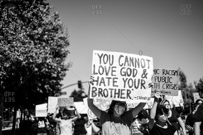 San Francisco Bay Area, California - June 8, 2020: Black Lives Matter protestors holding handmade signs reading "You cannot love God and hate your brother"