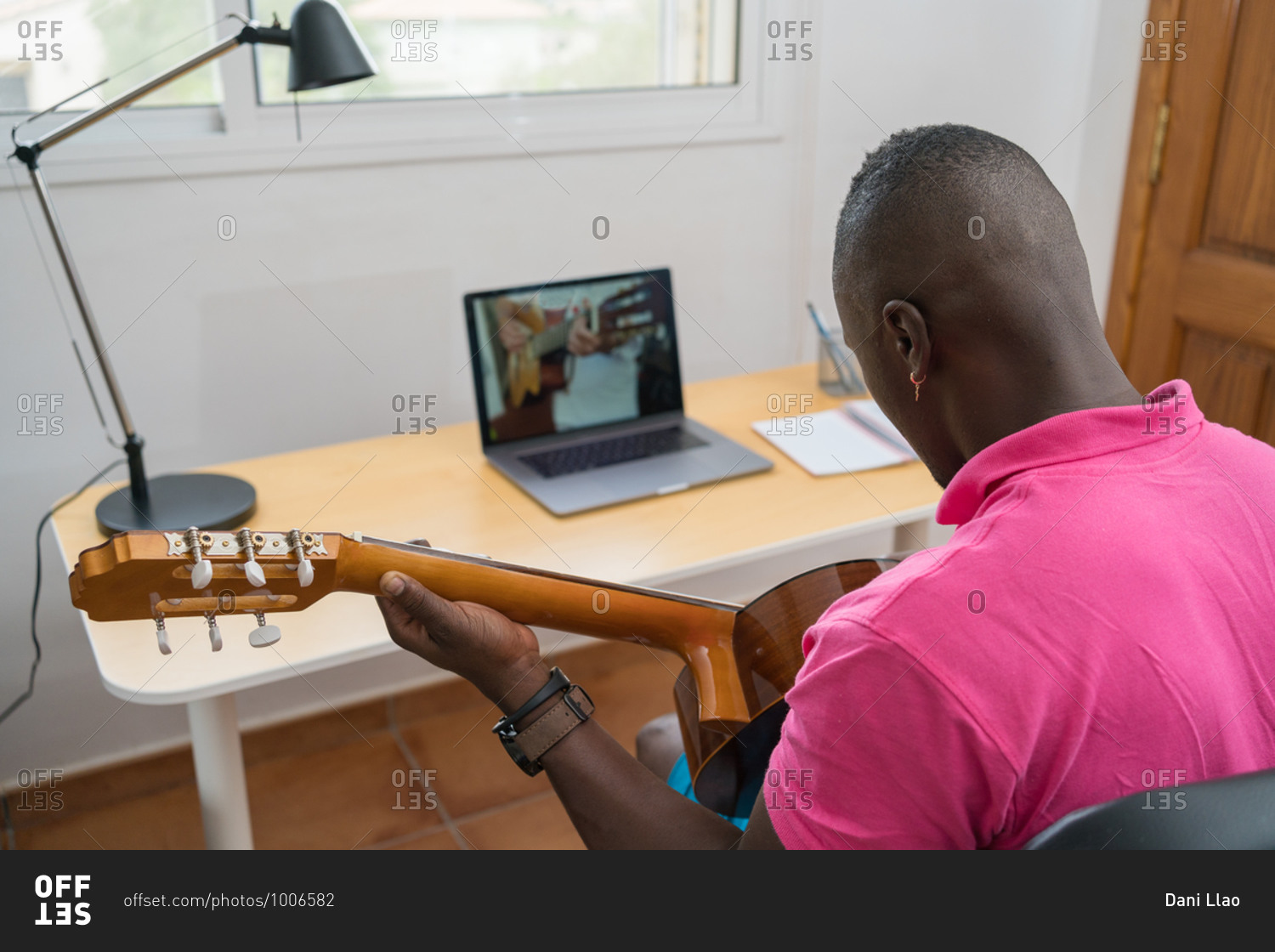 Young African-American man learning to play the guitar during an online class